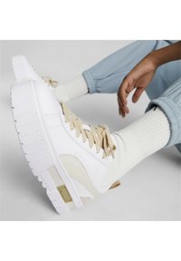 Białe trampki z grubą białą podeszwą, beżowymi sznurowadłami i akcentami. Posiadają gładką cholewkę i żebrowany detal po bokach podeszwy.