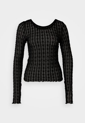 Must musternööbiga must pikkade varrukatega pluus, mis on valmistatud läbipaistvast, tekstureeritud kangast lainelise triibumustriga. Omab ümmargust kaelust ja volangidega varruka servi.