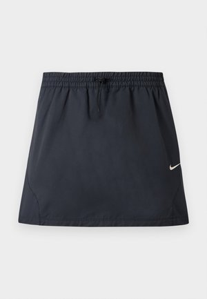 Fustă sport neagră cu talie elastică și șnur ajustabil, având un mic logo Nike alb în formă de swoosh pe partea dreaptă.