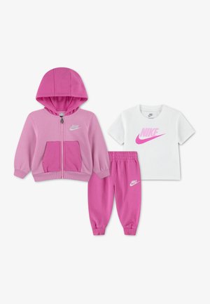 Ensemble Nike trois pièces pour enfants avec sweat à capuche rose, pantalon de jogging assorti rose et t-shirt blanc avec logo Nike rose.
