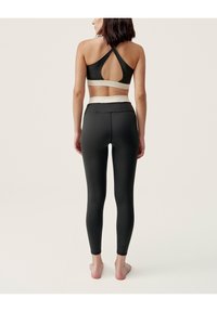 Black sports bra with a keyhole back and white trim, paired with high-waisted black leggings featuring a smooth texture and fitted design.