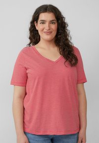 Rood-wit gestreepte T-shirt met V-hals en korte mouwen, gemaakt van zacht materiaal. Losse pasvorm met zijkanten, gecombineerd met blauwe spijkerbroek.