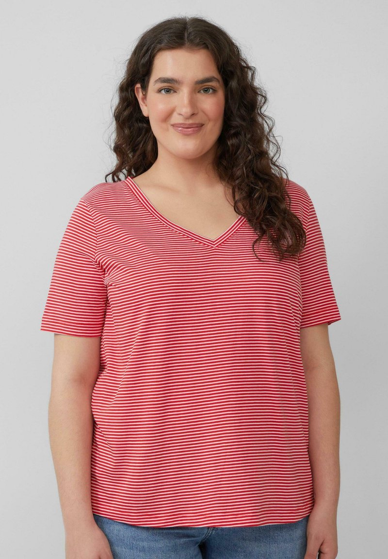 Rood-wit gestreepte T-shirt met V-hals en korte mouwen, gemaakt van zacht materiaal. Losse pasvorm met zijkanten, gecombineerd met blauwe spijkerbroek.