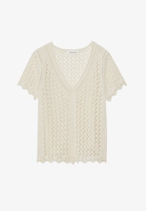 Top de punto de manga corta en crema con escote en V, patrón de zigzag, bordes ondulados y acabado texturizado. Ligero y de tejido abierto.