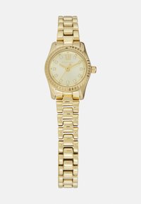 Montre-bracelet en or avec un cadran rond, un fond crème, des index en or et un bracelet à maillons métalliques. Présente une lunette texturée et une couronne.