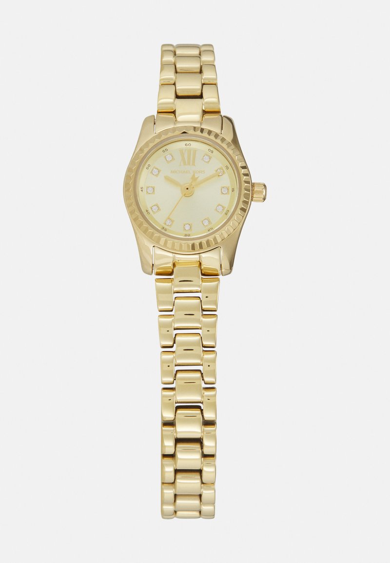 Montre-bracelet en or avec un cadran rond, un fond crème, des index en or et un bracelet à maillons métalliques. Présente une lunette texturée et une couronne.