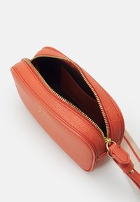 Borsa rettangolare arancione in pelle con superficie tessurizzata, chiusura con zip e zip dorata. Presenta una tracolla in tessuto con strisce e un interno foderato.