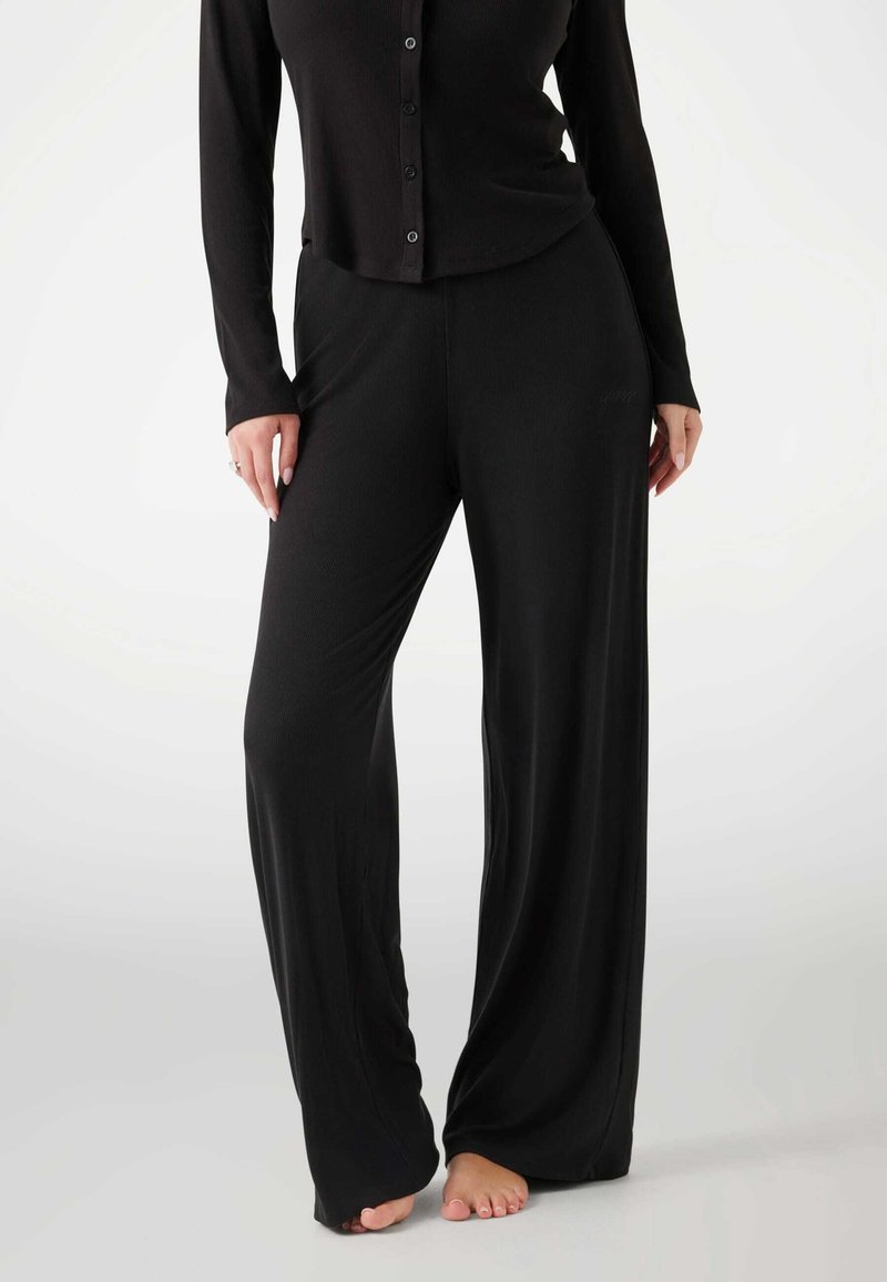Black long-sleeve button-up top paired with wide-leg black pants, made from soft fabric with a smooth texture, featuring a subtle logo detail.