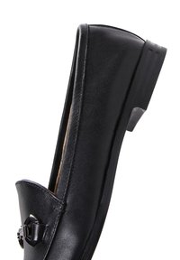 Black leather loafer with a rounded toe, slight heel, and decorative metal accent on the front. Smooth texture and sleek design.