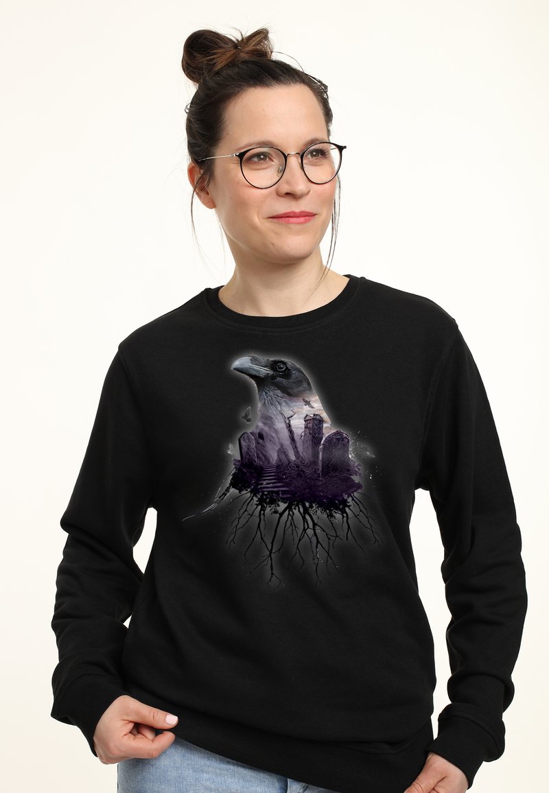 Černá mikina s potiskem grafiky hlavy havrana, která zahrnuje krajinu a kořeny, tištěná v odstínech šedé a fialové.