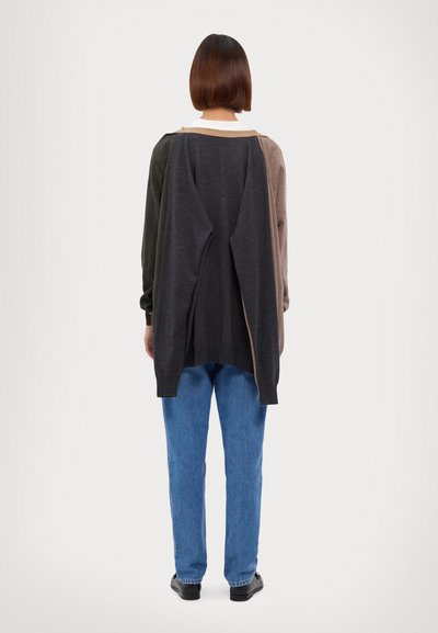 Maglione in diverse tonalità: grigio scuro, verde oliva e marrone chiaro, con una vestibilità comoda e design con spacco sul retro. Abbinato a jeans blu.