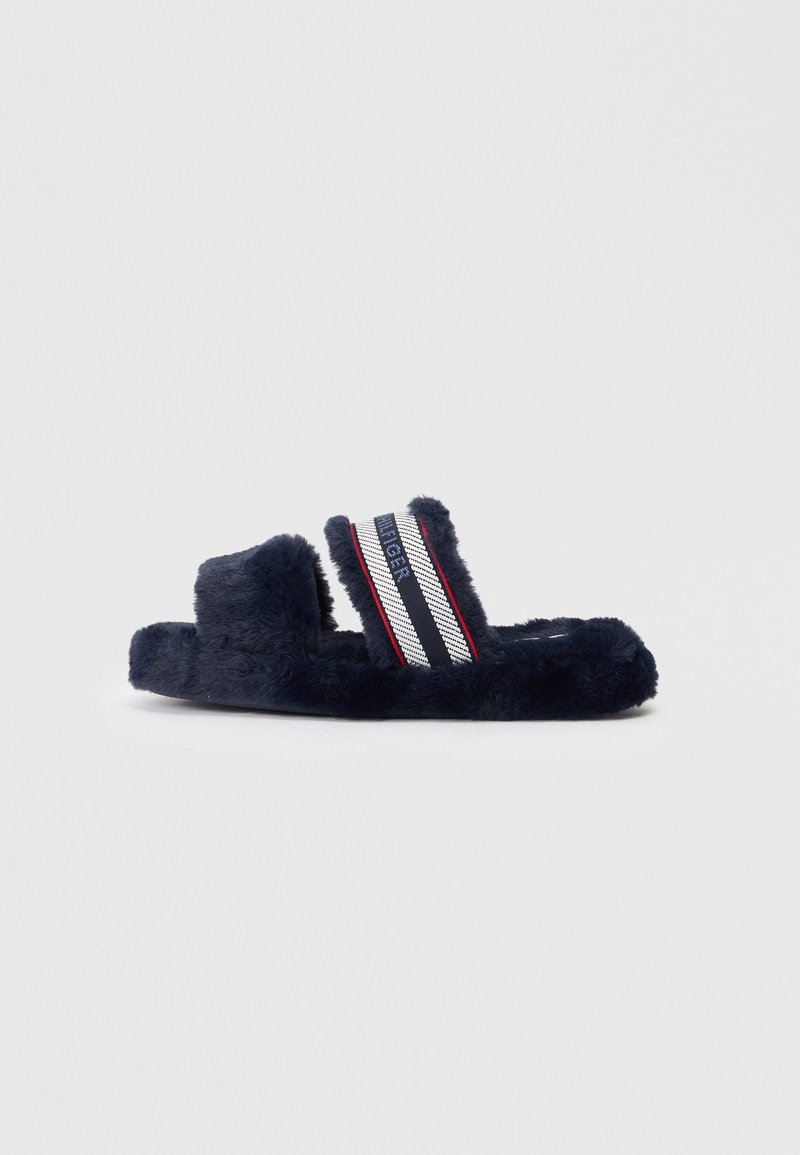 Mörkblå, fluffig slide-sandal med två breda remmar, som har ett randigt band i röd, vit och blå. Mjuk textur och öppen tå-design.