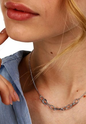 Silberne Halskette mit verbundenen ovalen und Achtformen. Zarter Kettenanhänger mit glatter Oberfläche, getragen auf einem hellblauen Hemd.
