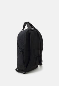 Černý batoh se strukturovaným designem, který obsahuje nastavitelné popruhy, boční kapsy a texturovaný materiál. Má minimalistickou estetiku.