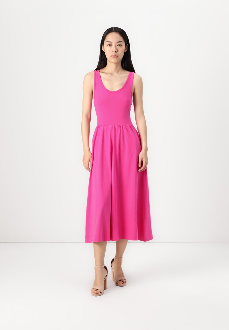 Rosa, tailliertes, ärmelloses Kleid mit Rundhalsausschnitt, ausgestelltem Rock und elastischem Bund. Die Model trägt beige, hochhackige Sandalen.