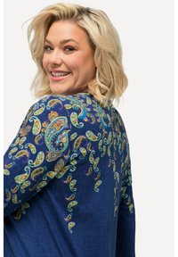 Blå långärmad topp med paisley-mönster i gult, grönt och lila. Slät tygstruktur med detaljerad broderi längs axlarna.