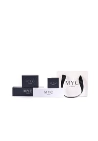 Scatole bianche e blu navy con il logo "MYC PARIS", in diverse dimensioni e forme, accompagnate da una borsa bianca con manici neri, anch'essa con il marchio.