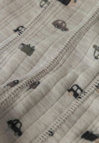 Baumwollstoff in hellbeige mit strukturierter Oberfläche, versehen mit einem Muster aus kleinen, bunten Autos in verschiedenen Farben und Stilen.