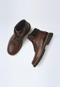 Brown leather ankle boots with a suede accent, round toe, lace-up design, and patterned rubber sole for grip.