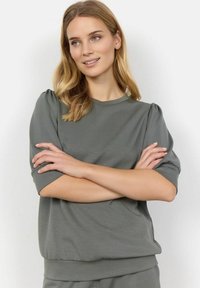 Top grigio a maniche corte in un tessuto morbido e leggero, con scollatura tonda e dettagli arricciati sulle spalle, che presenta una vestibilità comoda.