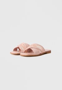 Pink slide sandals with lace details, soft material, open design, flat sole, and a light wooden accent on the bottom.