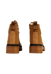 Tan enkellaarsjes van gestructureerd suede, met een stevige rubberen zool, treklussen en versterkte stiksels aan de achterkant.