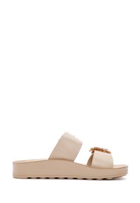 Beige synthetic slide sandals with two wide straps, embellished with a circular gold accent, and a textured platform sole.