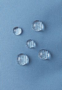 Niebieska tkanina o fakturze z pięcioma przezroczystymi kroplami wody na powierzchni, podkreślająca odporność na wodę oraz gładkie, błyszczące faktury.