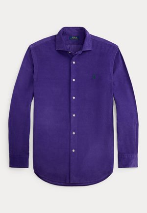 Fioletowa koszula sztruksowa na guziki z ostrym kołnierzykiem i długimi rękawami. Na przodzie znajduje się zielone haftowane logo oraz srebrne guziki.