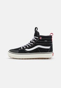 Svarte høyhælte sneakers laget av semsket skinn og gummi. Har en hvit stripe, polstret krage og rød hælflik. Hvite snører og teksturert såle.
