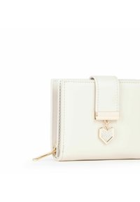 Cartera blanca de cuero con un broche dorado que presenta un encantador corazón adornado con cristales transparentes. Textura suave, forma rectangular.