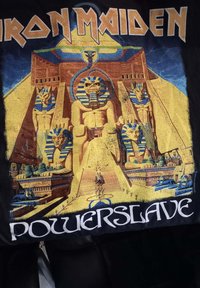 Zwarte katoenen t-shirt met een kleurrafische afbeelding van Egyptische standbeelden en piramides, met de tekst "Iron Maiden" en "Powerslave" in dikke letters.