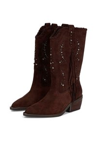 Botas de vaquero de ante marrón con punteras puntiagudas, tachuelas decorativas, flecos y bordes ondulados. Tacones apilados para mayor altura.