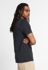 Camiseta de algodón negra con mangas cortas y corte recto, con cuello redondo y textura lisa.