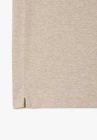 Beige tyg med en texturerad yta, med sidofickor vid fållen och tydliga sömmar. Enkel, minimalistisk design.