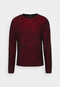 Pull rayé rouge et noir avec un col rond, des manches longues et une texture côtelée, conçu avec des couleurs contrastantes et une coupe décontractée.