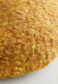 Rundes, strukturiertes Kissen in Gelb- und Orangetönen. Hergestellt aus einem flauschigen, weichen Material mit einem abwechslungsreichen Muster und einer leicht erhöhten Oberfläche.