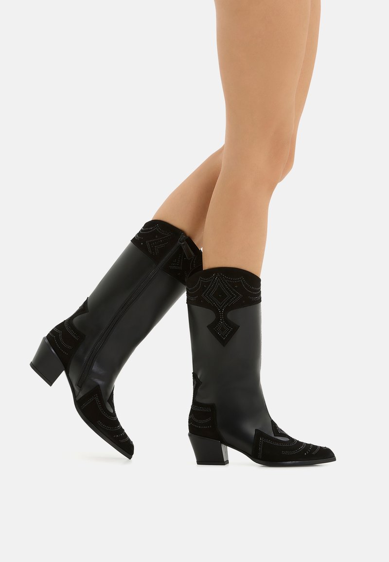 Stivali neri alti fino al ginocchio con una combinazione di pelle liscia e suede strutturato. Decorati con cuciture intricate e un tacco a blocco.