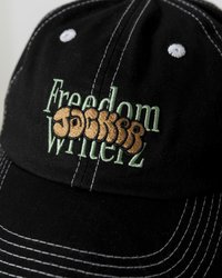 Black cap featuring embroidered text "Freedom" in green, and "JACKERZ" in brown. White stitching details on the brim and top button.