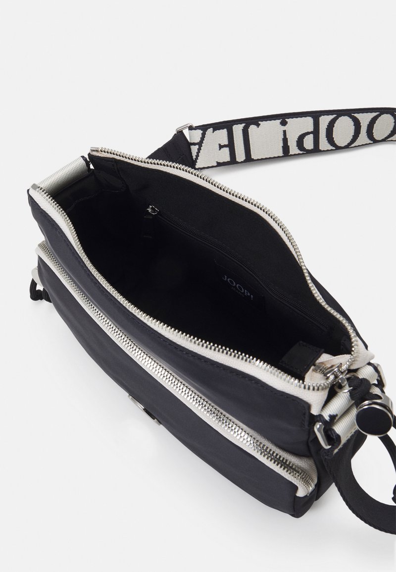 Schwarze Stofftasche mit silbernem Reißverschluss und einem strukturierten Stoffgurt, der ein kontrastierendes Logo zeigt. Das Innere enthält eine Reißverschlusstasche.