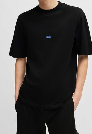 Schwarzes T-Shirt mit kurzen Ärmeln aus Baumwolle und rundem Ausschnitt; verfügt über ein kleines blaues "HUGO"-Logo auf der Brust.