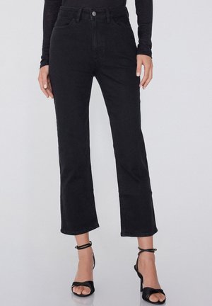 Pantalon en denim noir avec taille haute, coupe large et raccourcie, cinq poches et fermeture à bouton à l'avant. Le matériau semble lisse et robuste.