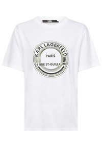 Witte katoenen T-shirt met een cirkelvormige zwarte en groene graphic met de tekst "Karl Lagerfeld," "Parijs," en "21 Rue St-Guillaume." Korte mouwen.