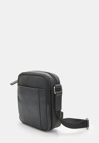 Borsa a tracolla nera con texture, chiusura a zip, tracolla regolabile e tasca frontale. Forma rettangolare compatta, design minimale.