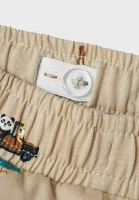 Beige elastisk talje med en hvid knap og løkke-lukning, prydet med broderede panda- og tiger-motiver i jordfarver.