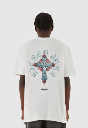 Weißes T-Shirt mit einer großen Grafik auf der Rückseite eines verzierten Kreuzes, mit filigranen blauen und roten Details und dem Text „HEILIGE KUNSTEN.“