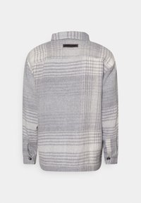 Camicia a quadri grigia e bianca, in materiale di lana, colletto standard, maniche lunghe con polsini a bottone e dettaglio sul retro.