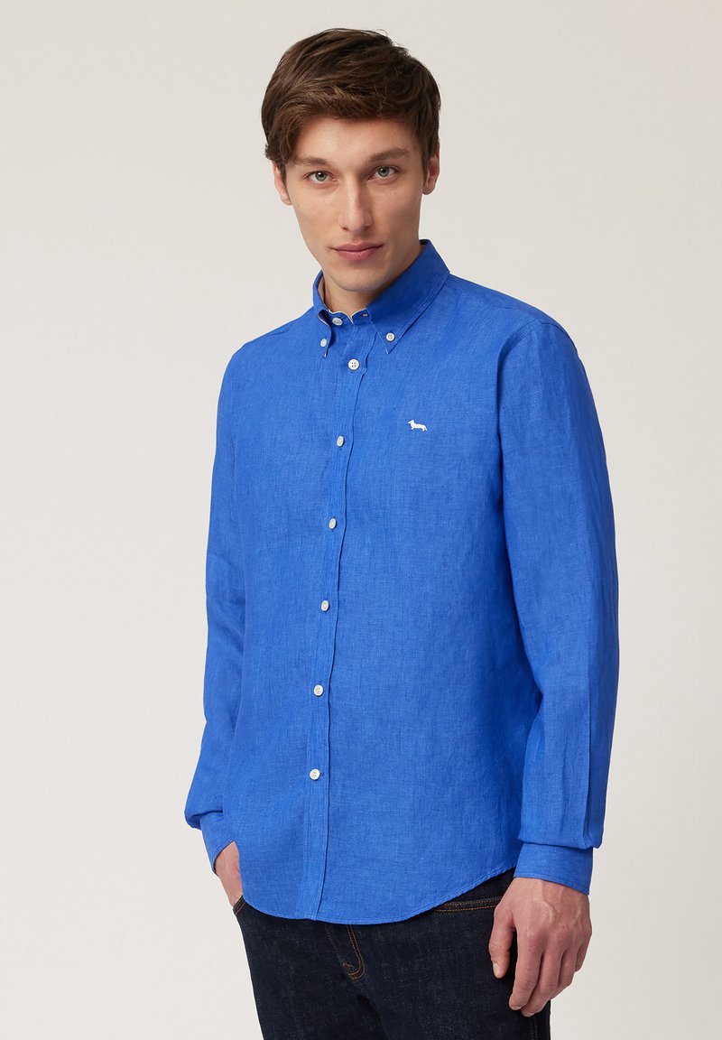 Camisa azul de manga larga en una tela ligera y texturizada. Cuenta con un cuello, botones blancos y un pequeño logo bordado.