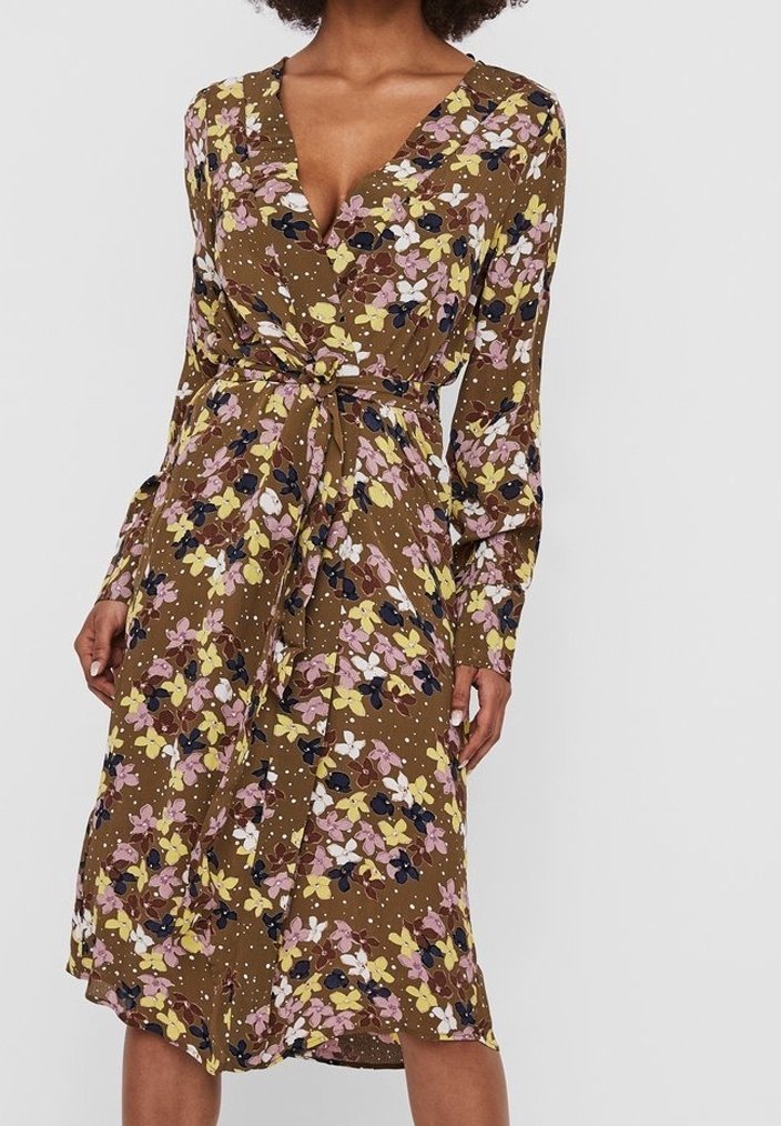 Robe portefeuille à manches longues, base marron, motif floral jaune, rose, blanc et noir, taille nouée et longueur au genou.