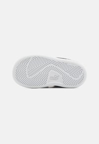 Schwarz-weißes Sneakerprofil mit einem Zickzackprofil. Verfügt über eine strukturierte Oberfläche und ein gummiertes Material, das keine Abdrücke hinterlässt. Logo vorhanden.